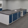 Angled view of 16' x 4' blue laboratory cabinets with black countertop and sink.