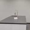 Side view of 16' x 4' blue laboratory cabinets with black countertop, desk cutout and sink.