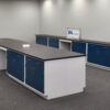 Angled view of 16' x 4' blue laboratory cabinets with black countertop, desk cutout and sink.
