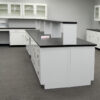 Side view of 16' x 4' white laboratory cabinets island. Center shelf centered across black countertop.