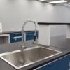 Close up of 16' blue laboratory island with center shelf and sink.
