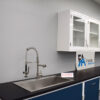 Laboratory cabinets with a sink and white wall units.